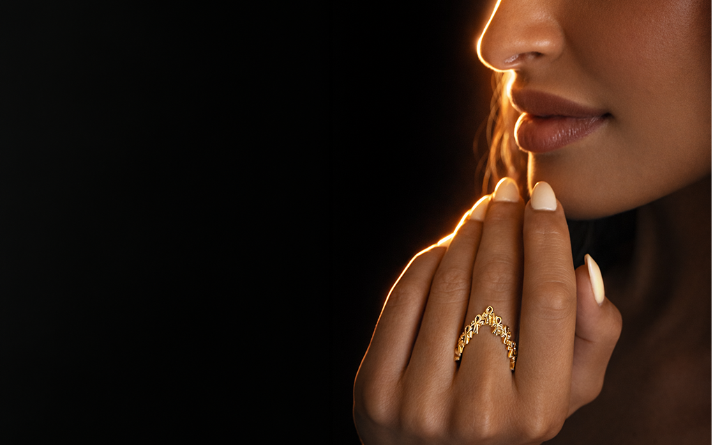 Woman wearing a gold ring on a dark background