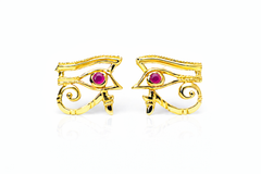Gold eye-shaped earrings with rubies set in the eyes on a white background