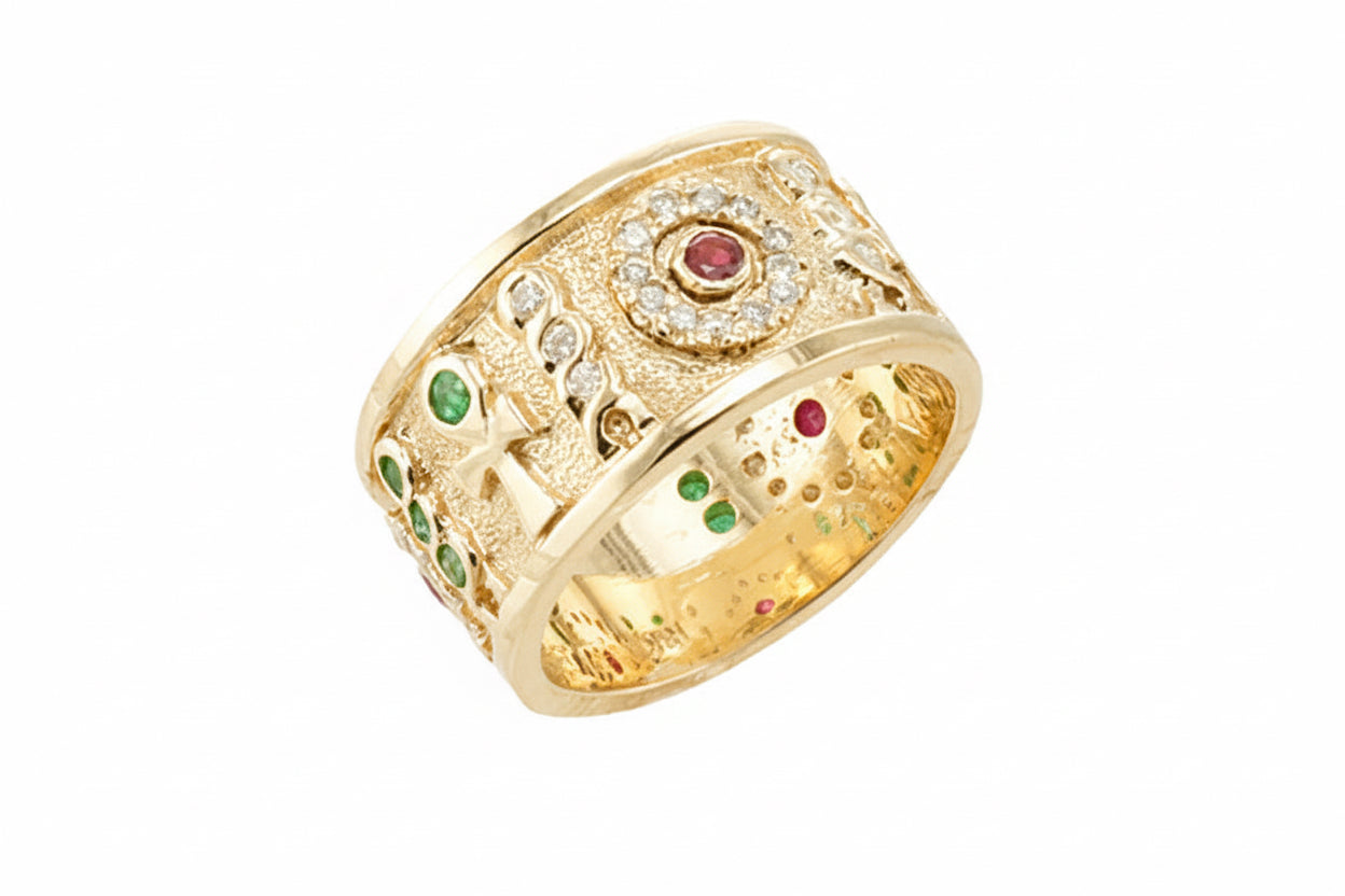 A gold band ring with diamonds, emeralds, and rubies set throughout, featuring an Ankh Heh Ra Heh hieroglyphic design which represents "Our Lives Shines Forever".