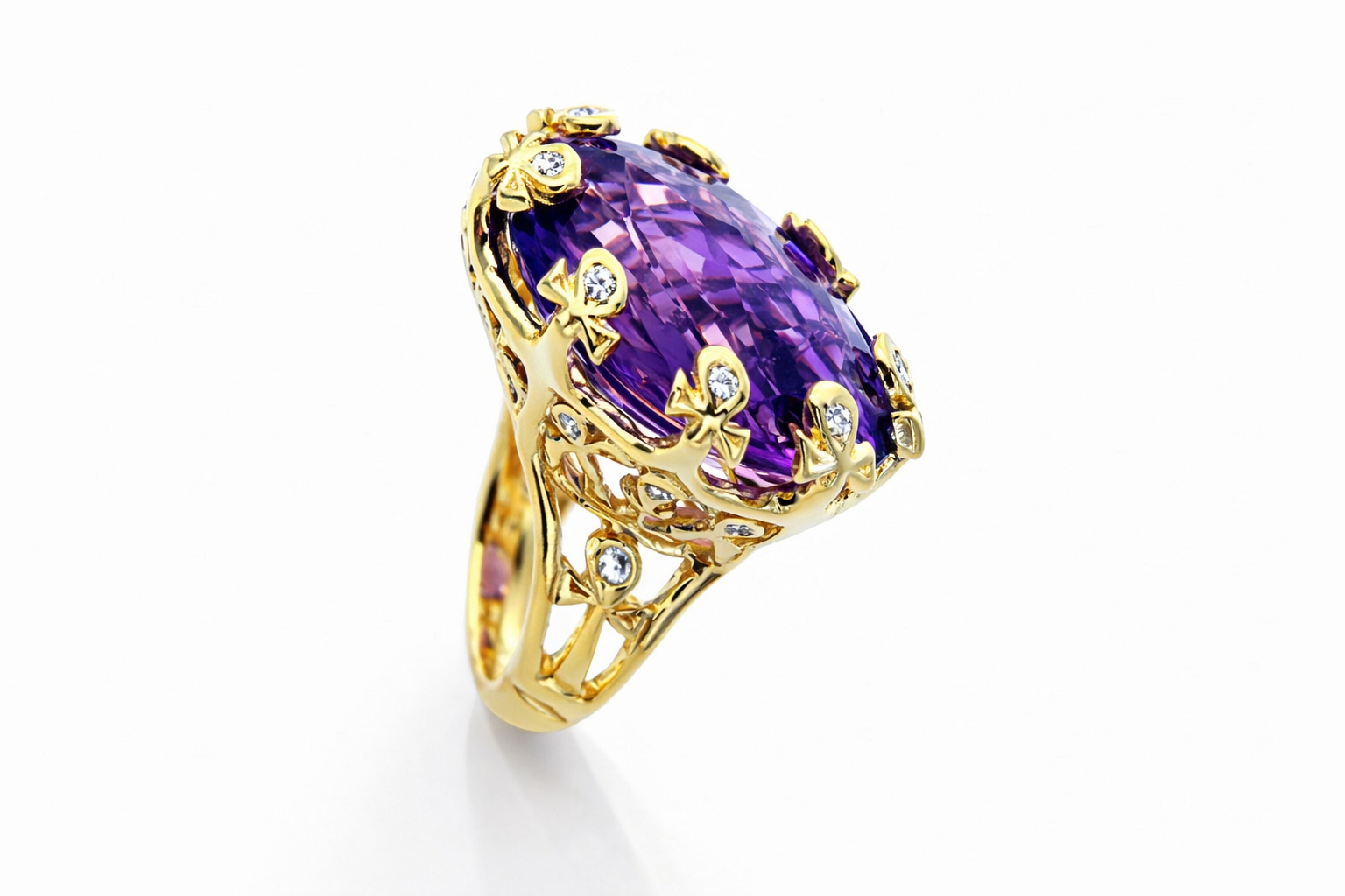 The Grand Cocktail Ring in yellow gold with a large purple gemstone on a white background