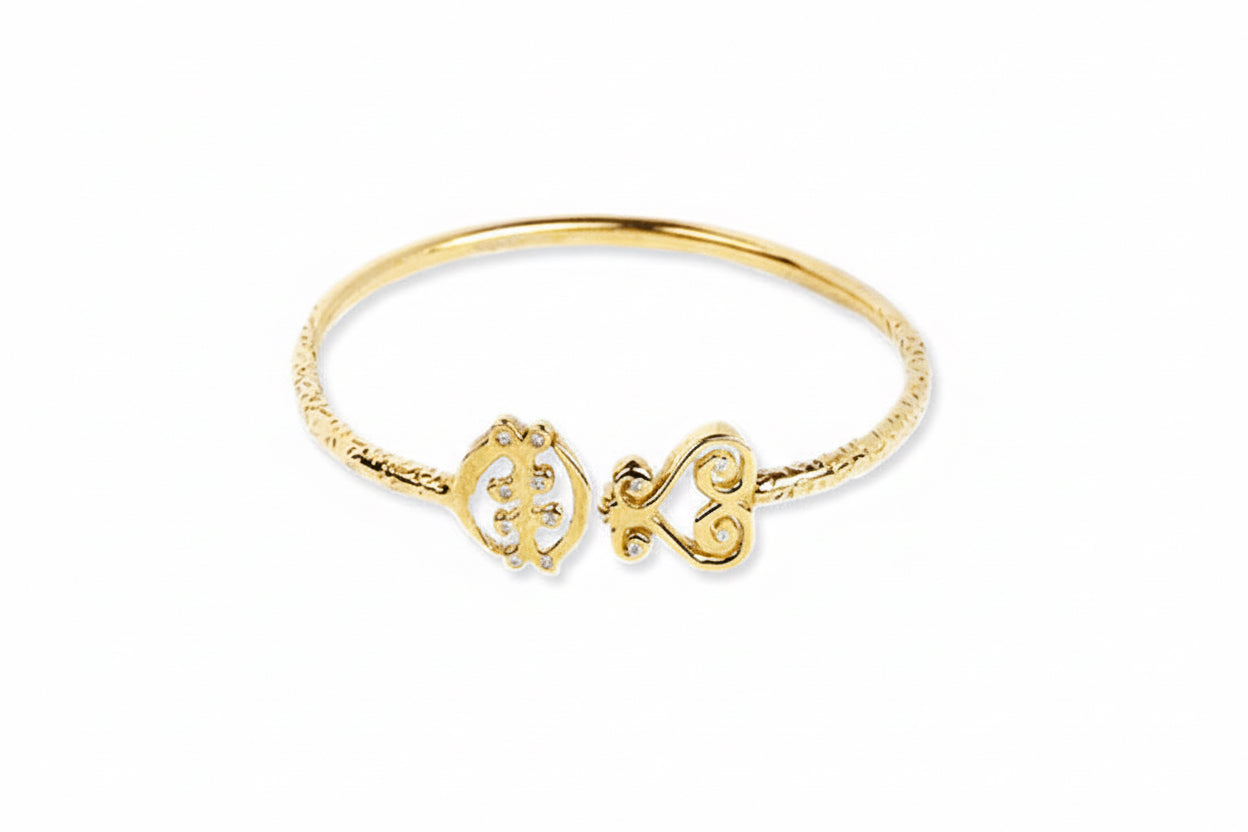 A 14k yellow gold Adinkra bangle bracelet with the symbols Gye Nyame and Sankofa on it, featuring white diamonds.