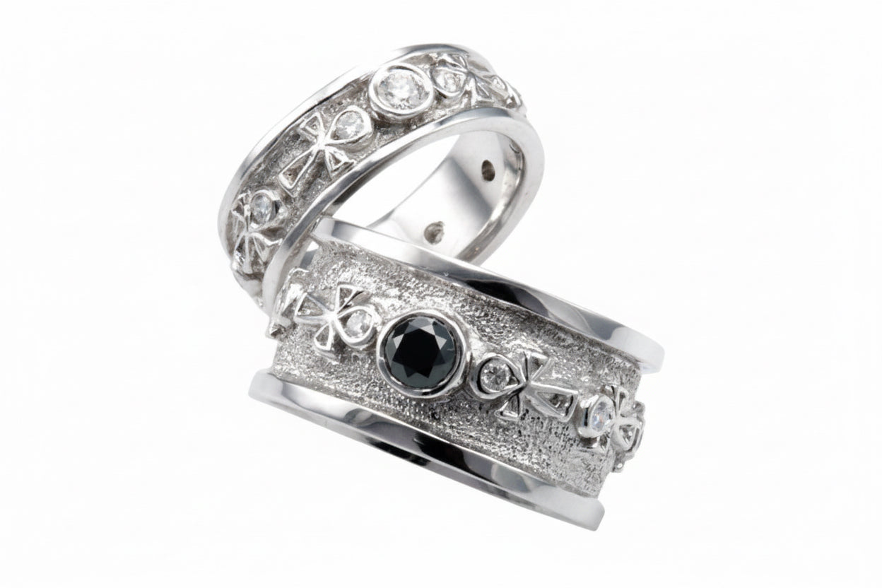 Two white gold ankh wedding rings with gemstones on a white background