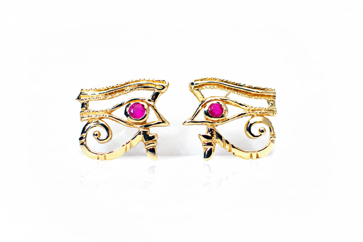 A pair of 14k yellow gold hoop earrings with red ruby eyes, against a white background.